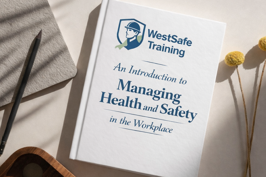 Book titled 'An Introduction to Managing Health and Safety in the Workplace' by WestSafe Training on a table with a pen and notebook.